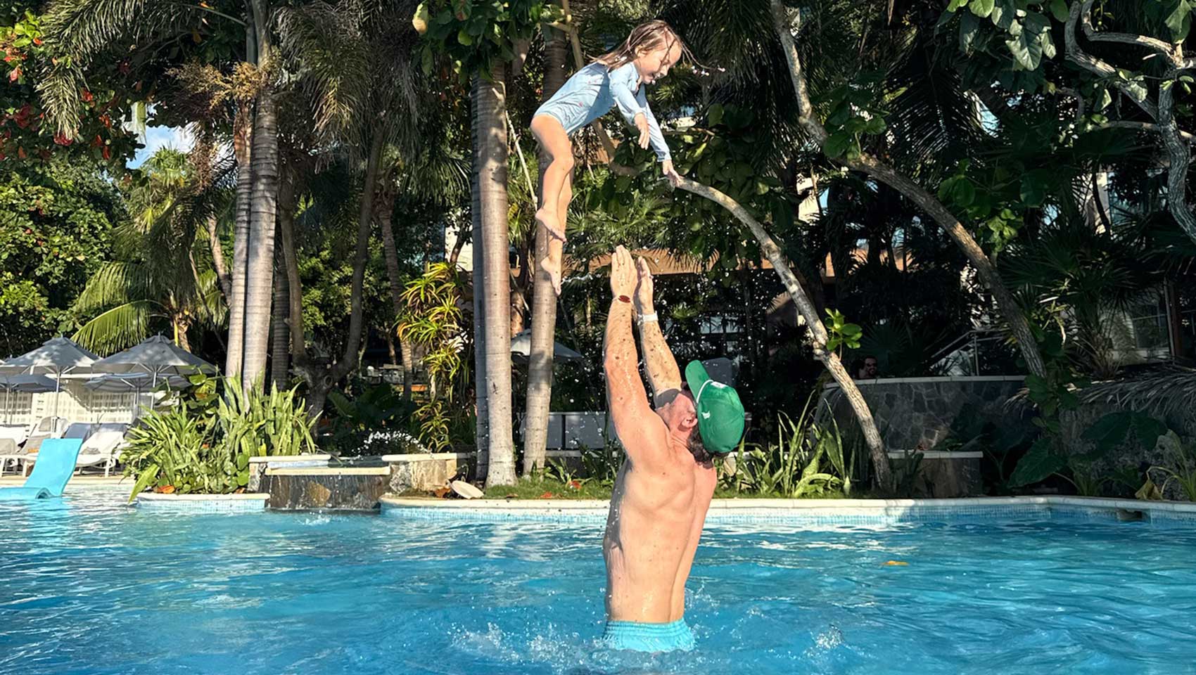 dad tossing kid up in the air in the pool