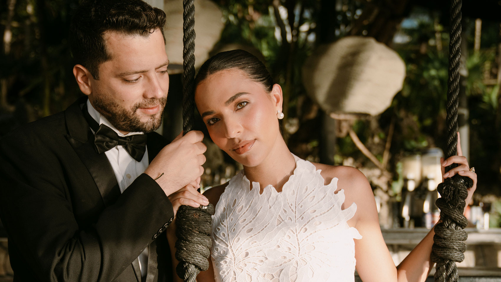 Bride on swing next to standing groom at Kimpton Grand Roatan