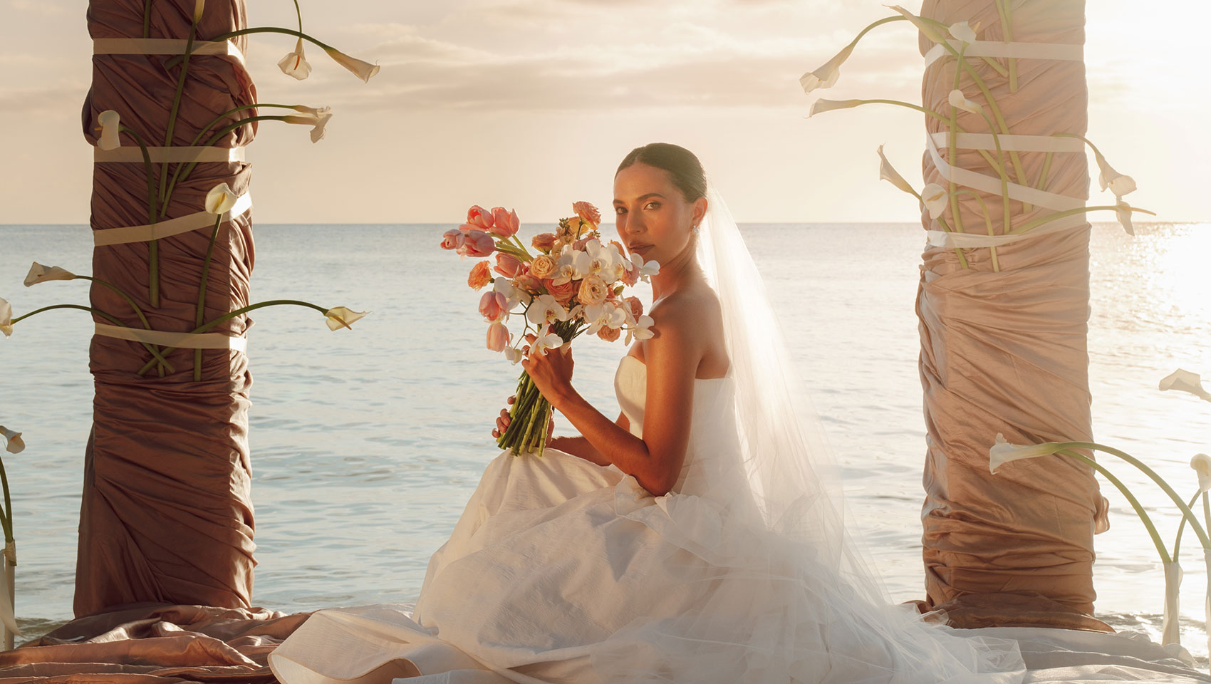 Bride poses with bouquet on custom ceremony beach set-up at Kimpton Grand Roatan