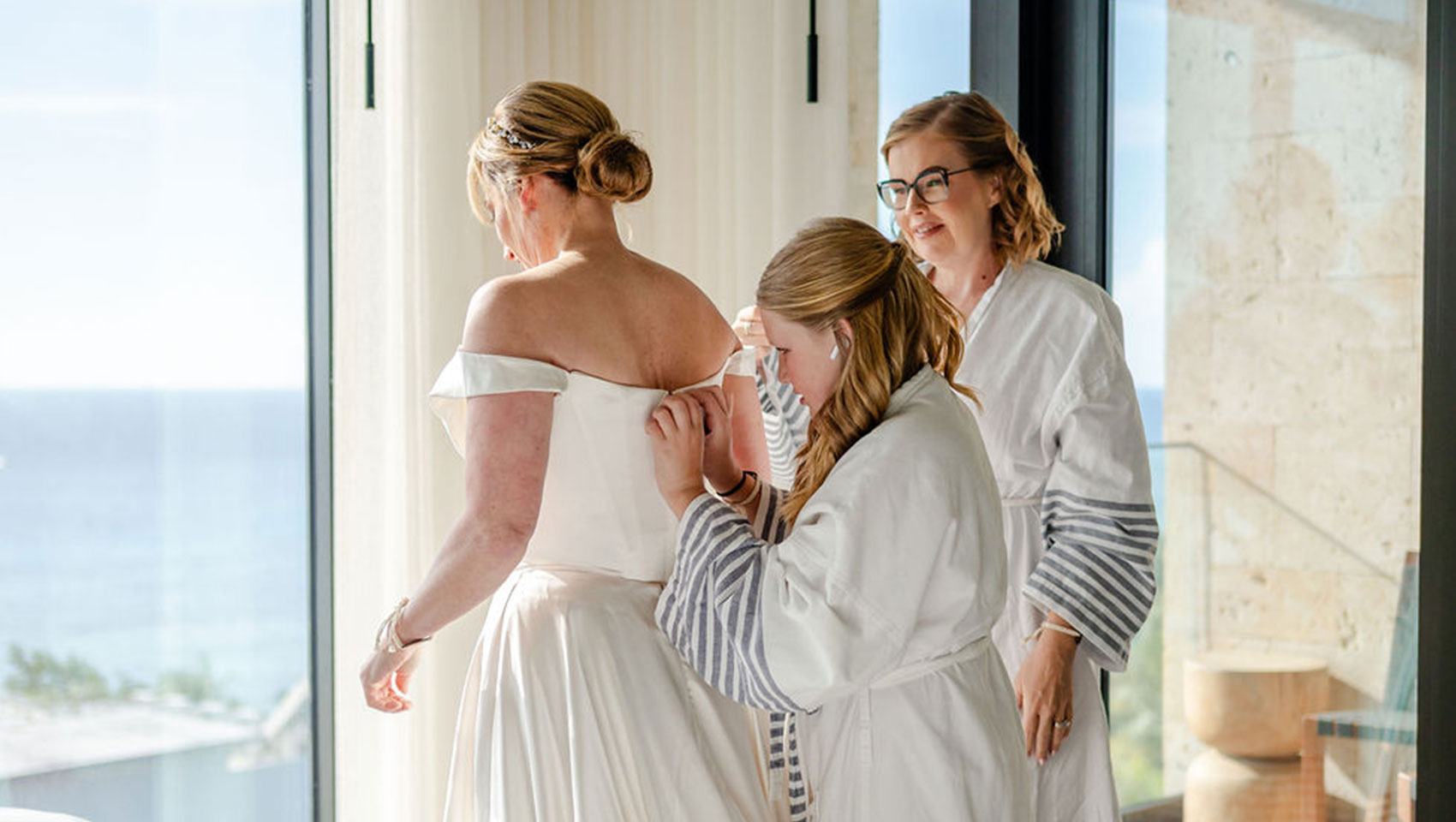 bridesmaid buttoning bride's dress at Kimpton Grand Roatan