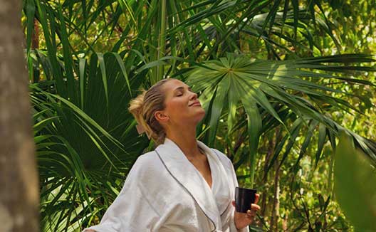 woman in robe outside at Grand Roatan holding a cup